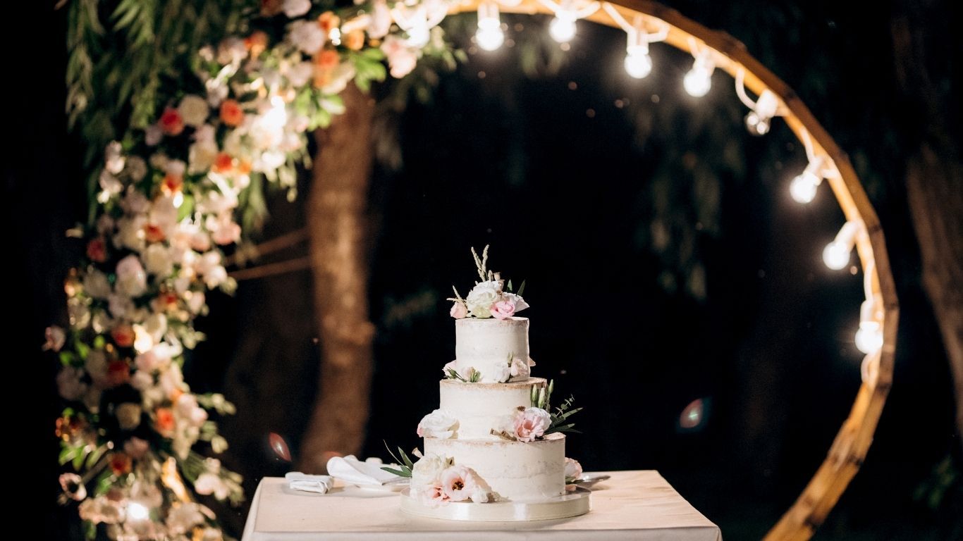Wedding cake beneath floral arch at night